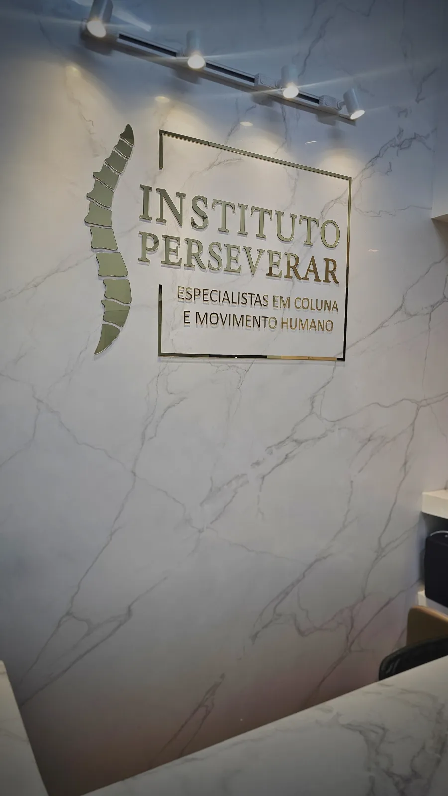 Recepção do Instituto Perseverar com logo dourado em parede de mármore